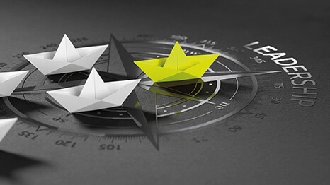 Gelbes Papierschiff führt weiße Schiffe auf einem Kompass – Leadership