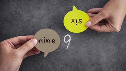 Zwei Hände halten Sprechblasen mit 'nine' und 'six'